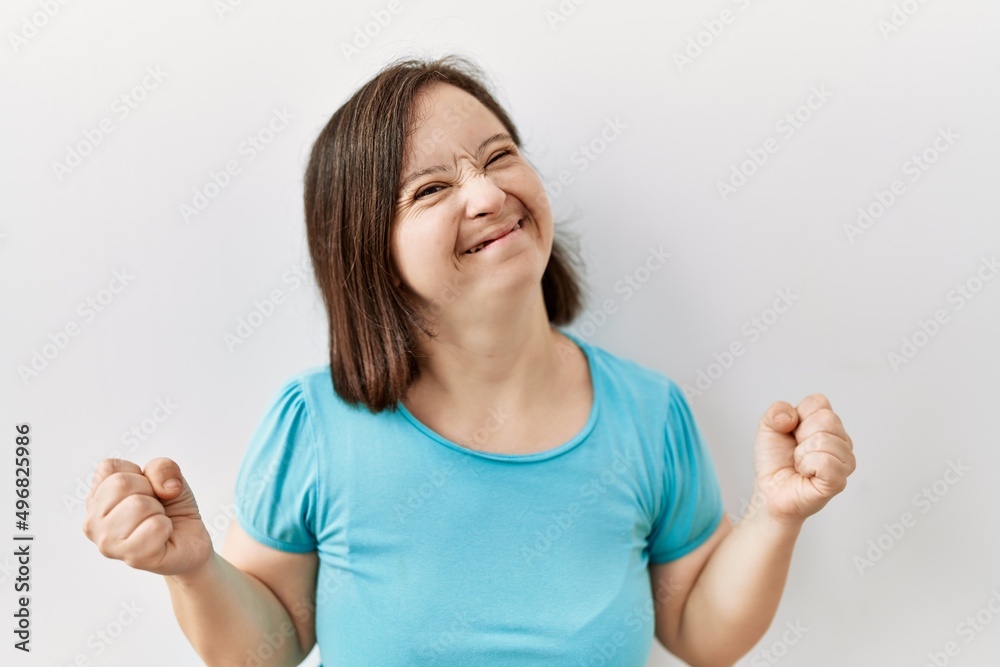 Young down syndrome woman standing over isolated background very happy and excited doing winner gesture with arms raised, smiling and screaming for success. celebration concept. Young down syndrome woman standing over isolated background very happy and excited doing winner gesture with arms raised, smiling and screaming for success. celebration concept.