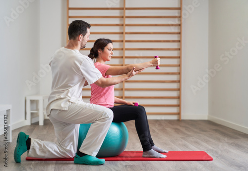 Obraz na płótnie physiotherapist helping his patient to correct posture to avoid back pains