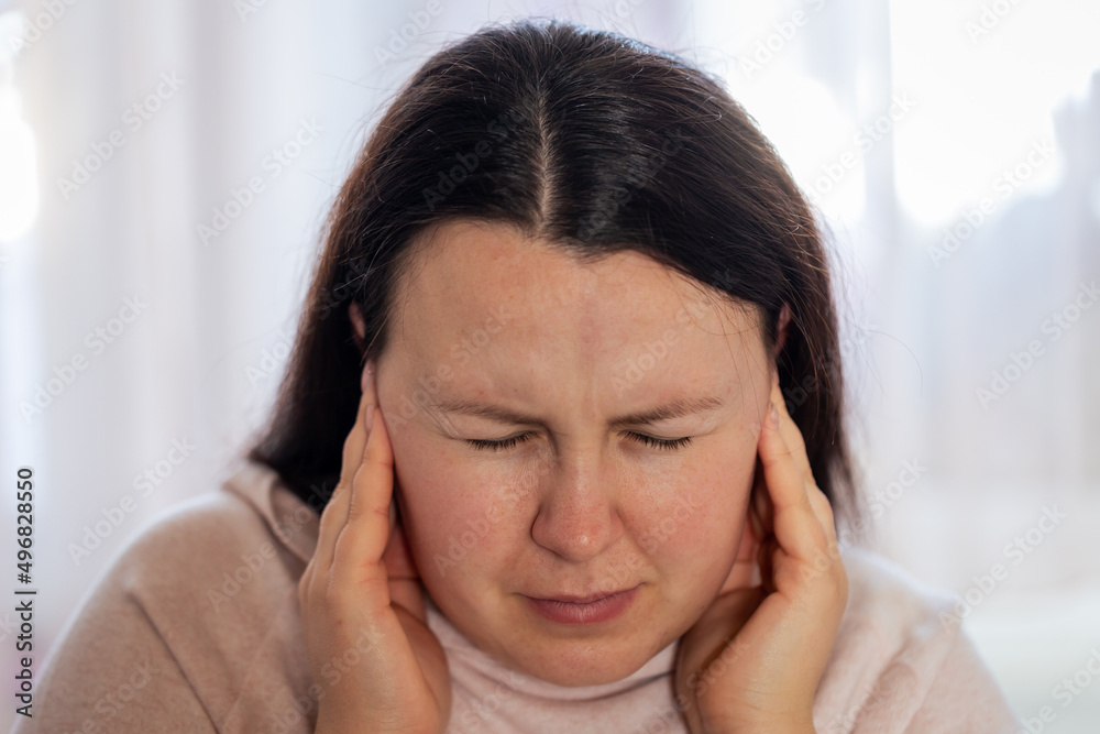 Young woman have a headache migraine stress or tinnitus - noise whistling in her ears. Young woman have a headache migraine stress or tinnitus - noise whistling in her ears.