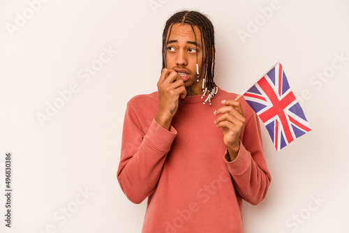 Young African American man holding a English flag isolated on white background relaxed thinking about something looking at a copy space.