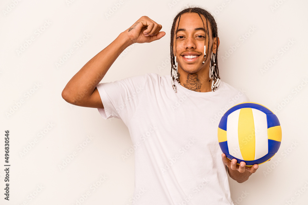 Young African American man playing volleyball isolated on white background raising fist after a victory, winner concept.