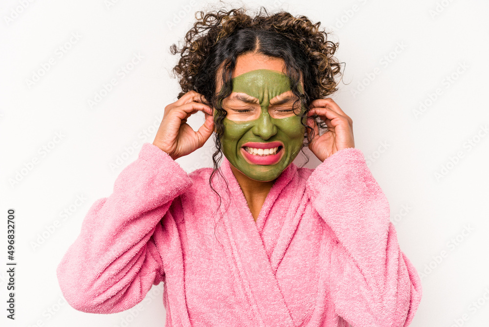 Young hispanic woman wearing a facial mask isolated on white background covering ears with hands. Young hispanic woman wearing a facial mask isolated on white background covering ears with hands.