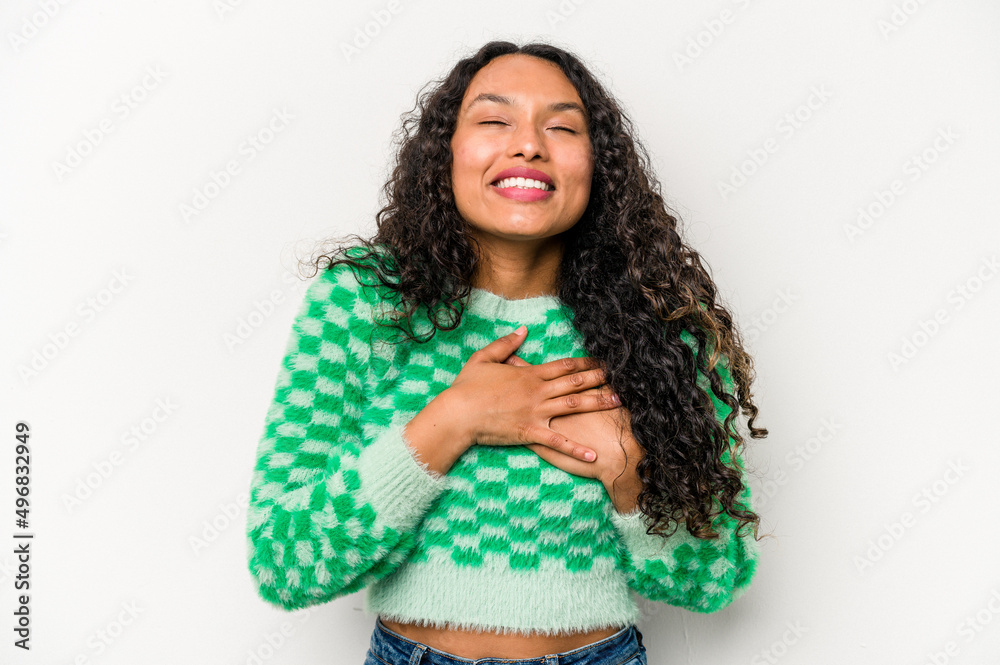 Young hispanic woman isolated on white background laughing keeping hands on heart, concept of happiness.