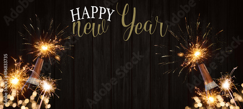 HAPPY NEW YEAR 2023 celebration Silvester New Year's Eve Party background banner greeting card - Champagne bottles with fireworks and sparklers on dark wooden wood wall texture in the night