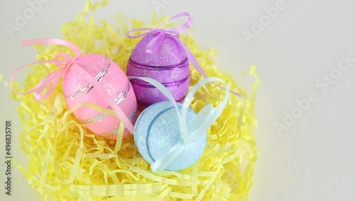 Three colored eggs lie in the nest on a white background with copyspace view from the side of Von Easter.