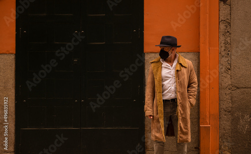 Portrait of adult man in hat and mask against wall on street. Madrid, Spain