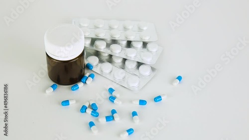 falling blue pills on pile of capsules on white background.