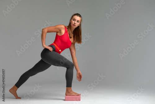 Girl does exercises with foam block. Yoga practice for beginners. Sporty woman in sportswear using yoga bricks