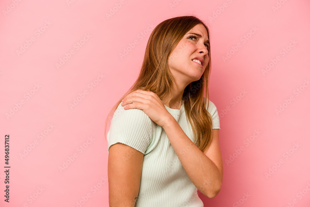 Young caucasian woman isolated on pink background having a shoulder pain. Young caucasian woman isolated on pink background having a shoulder pain.