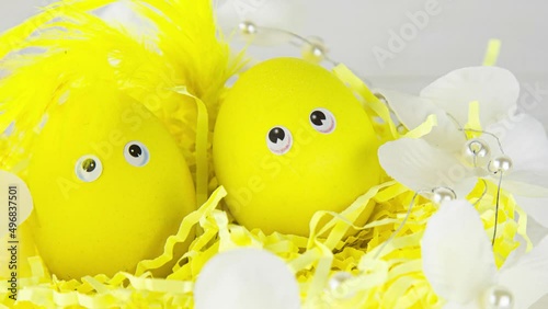 Decorative basket with yellow eggs decorated with feathers in the sun.