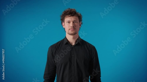 Portrait furious curly man aggressive gesture trying strangle kill posing isolated on blue studio photo