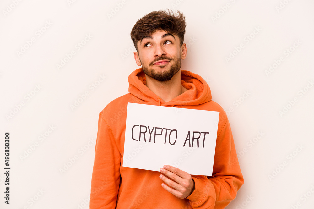 Young hispanic man holding a crypto art placard isolated on white background dreaming of achieving goals and purposes Young hispanic man holding a crypto art placard isolated on white background dreaming of achieving goals and purposes