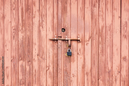 Wooden door background. Garage door texture. Abandoned locked gate. Metal padlock with peeling paint.