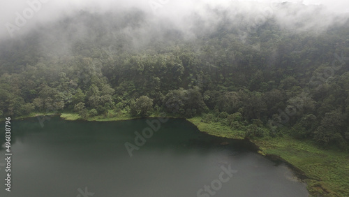 Aerial view of Ranamese lake in Indonesia with a forest and fog above it photo