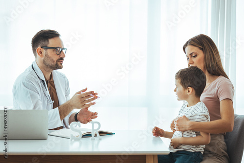Caring medical doctor examining a little girl in office. Cute child and doctor talking in clinics. Happy male doctor have fun cheer support small 7s boy patient at visit to clinic with mom.