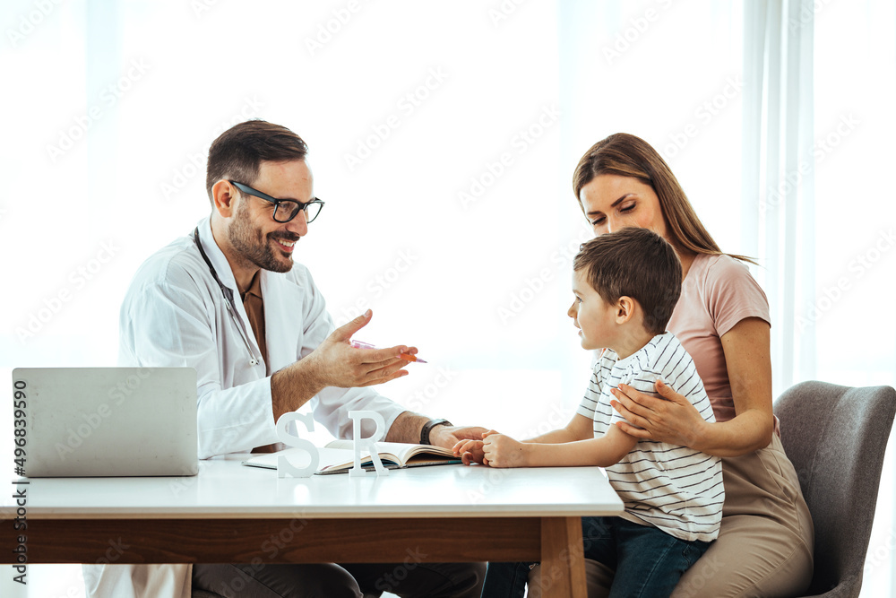 Caring medical doctor examining a little girl in office. Cute child and doctor talking in clinics. Happy male doctor have fun cheer support small 7s boy patient at visit to clinic with mom. Caring medical doctor examining a little girl in office. Cute child and doctor talking in clinics. Happy male doctor have fun cheer support small 7s boy patient at visit to clinic with mom.