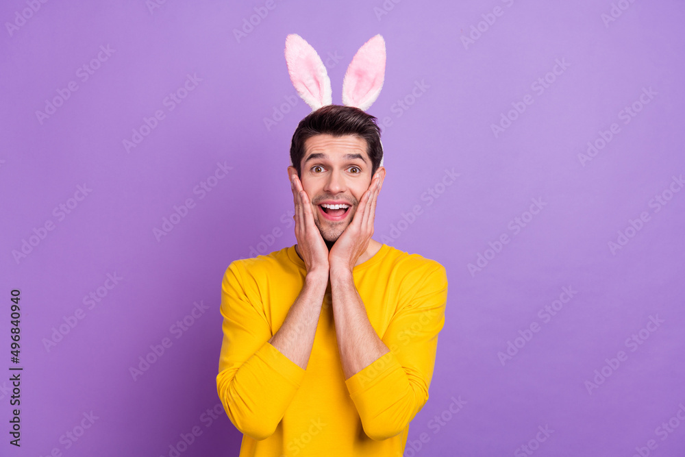 Photo of cheerful laughing young man with bunny ears see huge bargains on black friday isolated on purple color background Photo of cheerful laughing young man with bunny ears see huge bargains on black friday isolated on purple color background