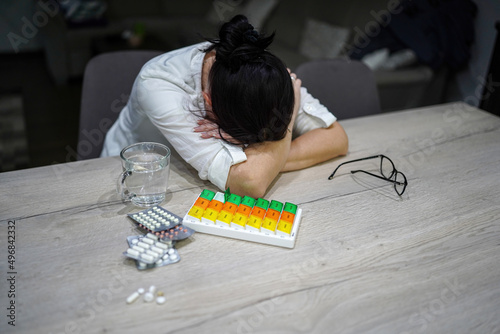 young woman preparing medication at home at the table exhausted, tired