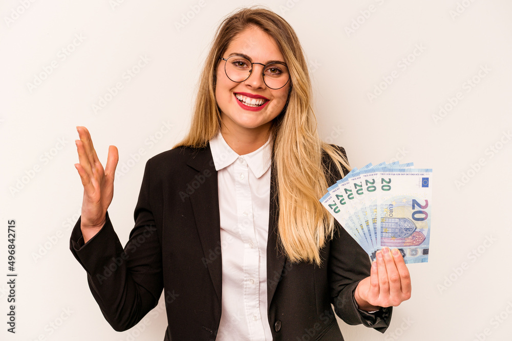 Young business caucasian woman holding a banknotes isolated on white background receiving a pleasant surprise, excited and raising hands. Young business caucasian woman holding a banknotes isolated on white background receiving a pleasant surprise, excited and raising hands.