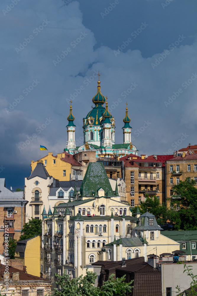 View of the church from the hill. Houses of different styles in Kyiv. Church with dark green domes. Church in baroque style