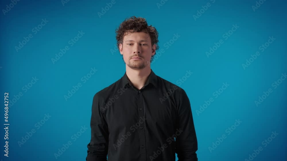 Portrait curly celebrity man hiding face no shooting camera hand closed posing isolated on blue