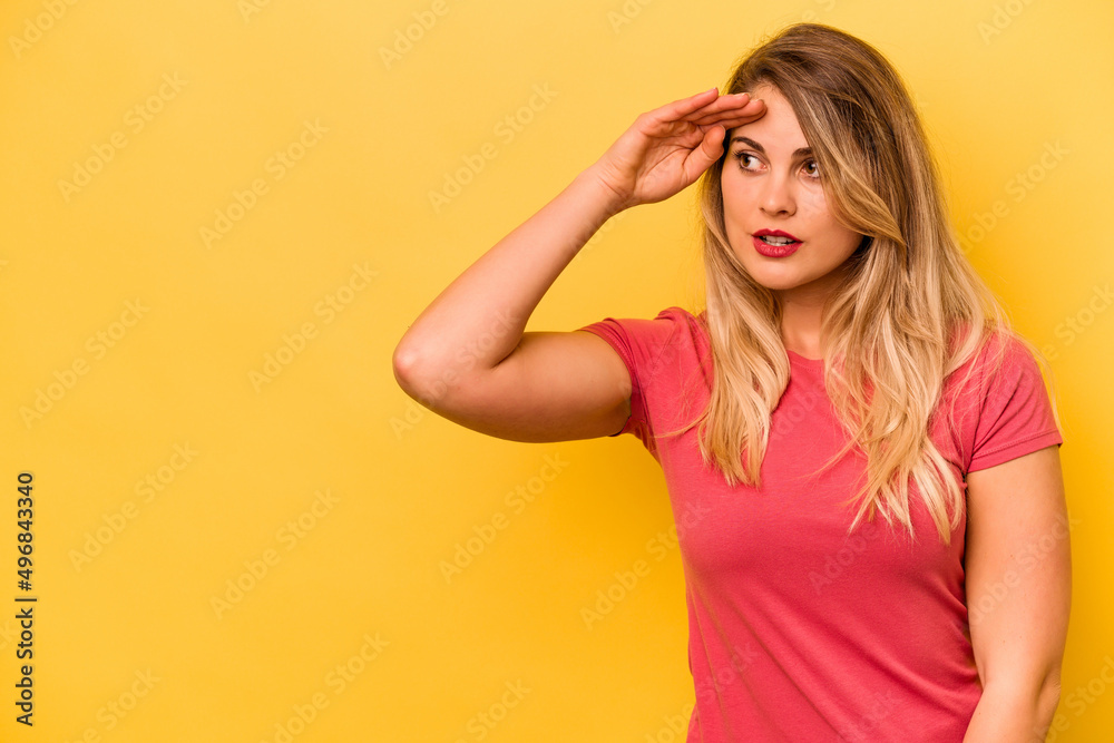 Young caucasian woman isolated on yellow background looking far away keeping hand on forehead.
