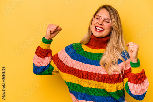 Young caucasian woman isolated on yellow background raising fist after a victory, winner concept.