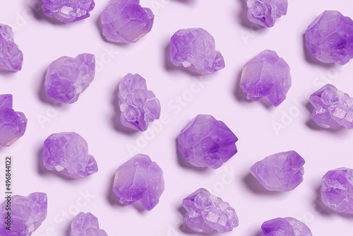 Creative pattern of purple amethyst crystals on very peri color background,  top view natural beautiful gemstone as geometric layout. Amethyst stone healing crystal, precious gem, flat lay