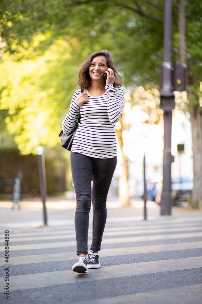Full body smiling young woman walking and talking with mobile phone Full body smiling young woman walking and talking with mobile phone