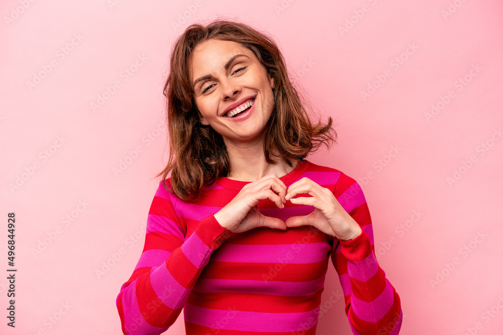 Young caucasian woman isolated on pink background smiling and showing a heart shape with hands. Young caucasian woman isolated on pink background smiling and showing a heart shape with hands.