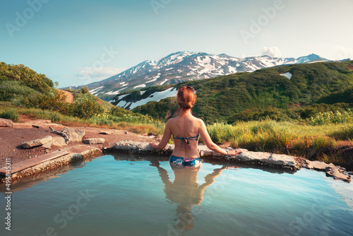 Beautiful woman in a natural thermal pool with a mountain view. Hot thermal springs in Kamchatka peninsula, Russia. Summer travel concept