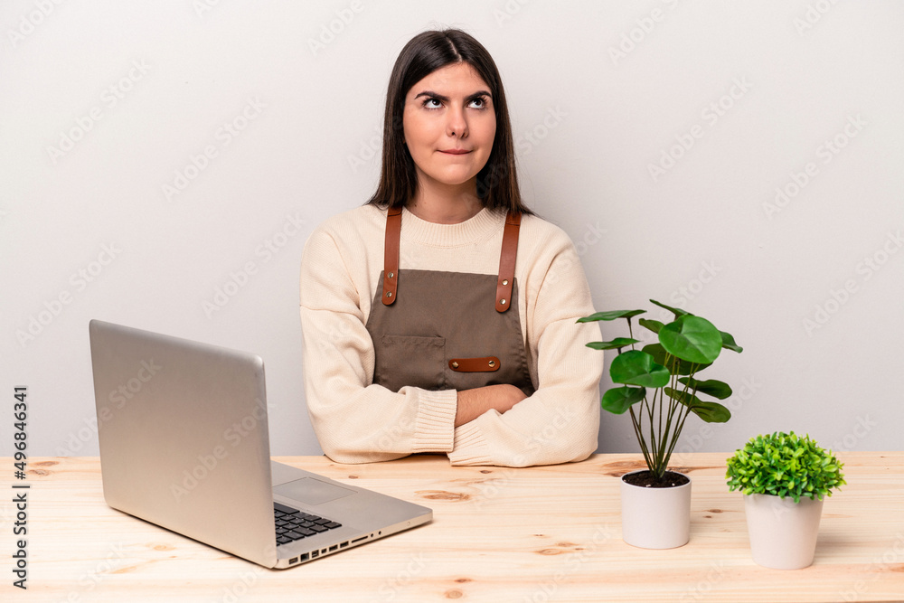 Young caucasian gardener woman working on the table isolated on pink background confused, feels doubtful and unsure. Young caucasian gardener woman working on the table isolated on pink background confused, feels doubtful and unsure.