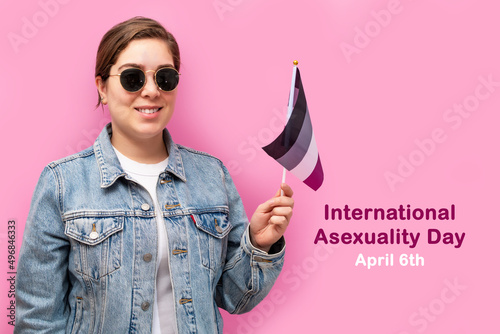 International Asexuality Day. Happy girl hold asexual flag, on pink background. photo