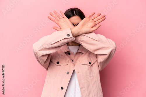 Young caucasian woman isolated on pink background keeping two arms crossed, denial concept. photo