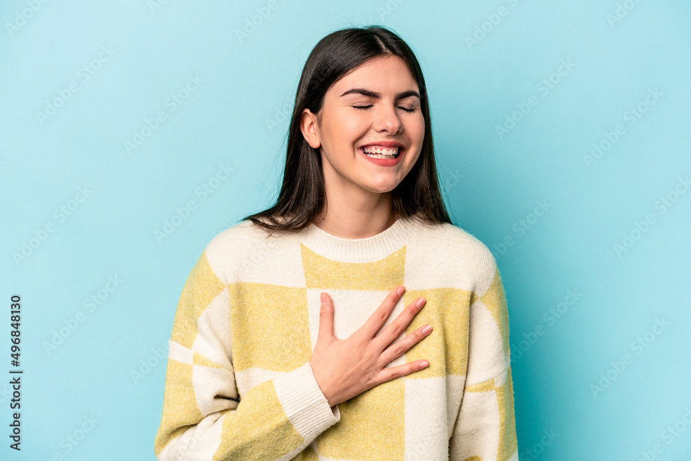 Young caucasian woman isolated on blue background laughs out loudly keeping hand on chest. Young caucasian woman isolated on blue background laughs out loudly keeping hand on chest.