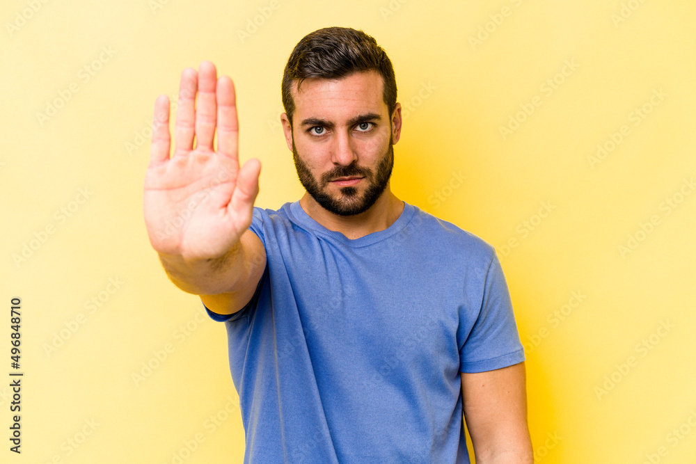 Young caucasian man isolated on yellow background standing with outstretched hand showing stop sign, preventing you. Young caucasian man isolated on yellow background standing with outstretched hand showing stop sign, preventing you.