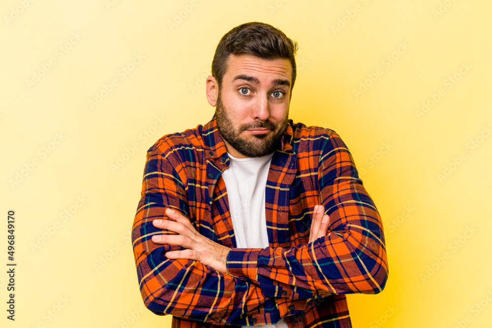 Young caucasian man isolated on yellow background shrugs shoulders and open eyes confused. Young caucasian man isolated on yellow background shrugs shoulders and open eyes confused.