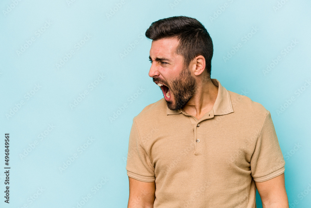 Fototapeta premium Young caucasian man isolated on blue background shouting very angry, rage concept, frustrated.