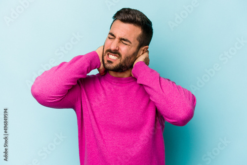 Young caucasian man isolated on blue background suffering neck pain due to sedentary lifestyle.