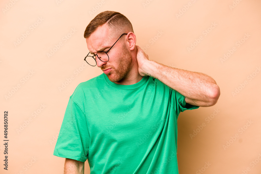 Young caucasian man isolated on beige background having a neck pain due to stress, massaging and touching it with hand. Young caucasian man isolated on beige background having a neck pain due to stress, massaging and touching it with hand.