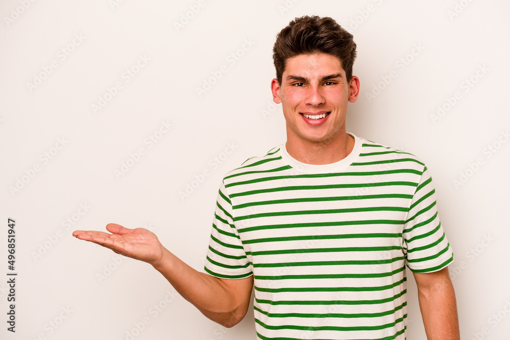 Young caucasian man isolated on white background showing a copy space on a palm and holding another hand on waist. Young caucasian man isolated on white background showing a copy space on a palm and holding another hand on waist.
