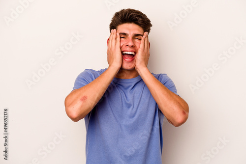 Young caucasian man isolated on white background laughs joyfully keeping hands on head. Happiness concept.