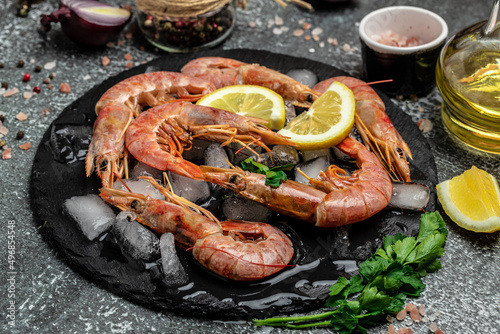 Red Argentine shrimps with ice and lemon, Wild shrimps, ocean jumbo shrimps on a dark background. Restaurant menu, dieting, cookbook recipe top view