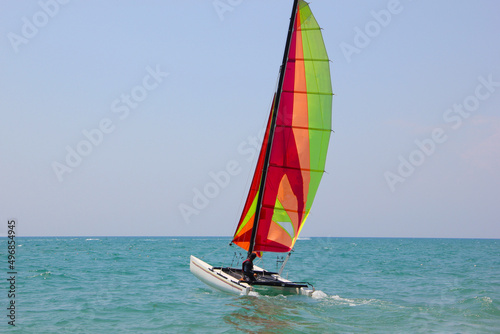 a yacht with a raised sail departs from the shore into the sea
