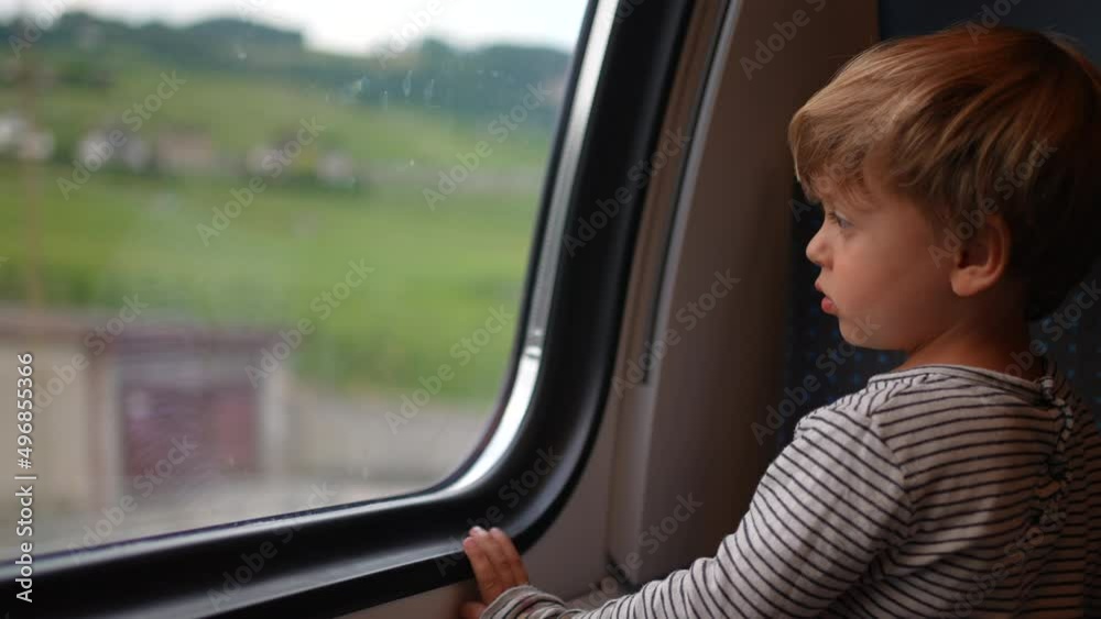 Child staring out train window looking at landscape pass by Child staring out train window looking at landscape pass by