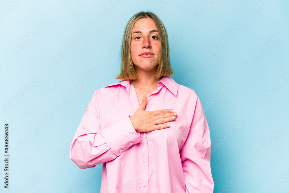 Young caucasian woman isolated on blue background taking an oath, putting hand on chest. Young caucasian woman isolated on blue background taking an oath, putting hand on chest.