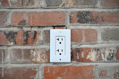 Closeup shot of an electrical socket in a brick wall photo
