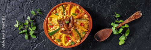 Meat and vegetable couscous panorama. Traditional Moroccan dish, overhead flat lay shot on a dark background