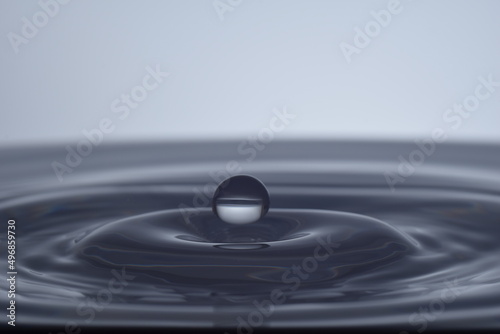 Kropla nad taflą wody na jasnym tle