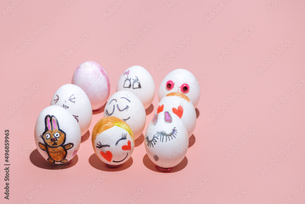 Easter eggs painted by children with different painted faces are placed on a pink background. Emotions of joy, love and shyness. Pink bunny. Minimal concept. Look straight, copy space.
